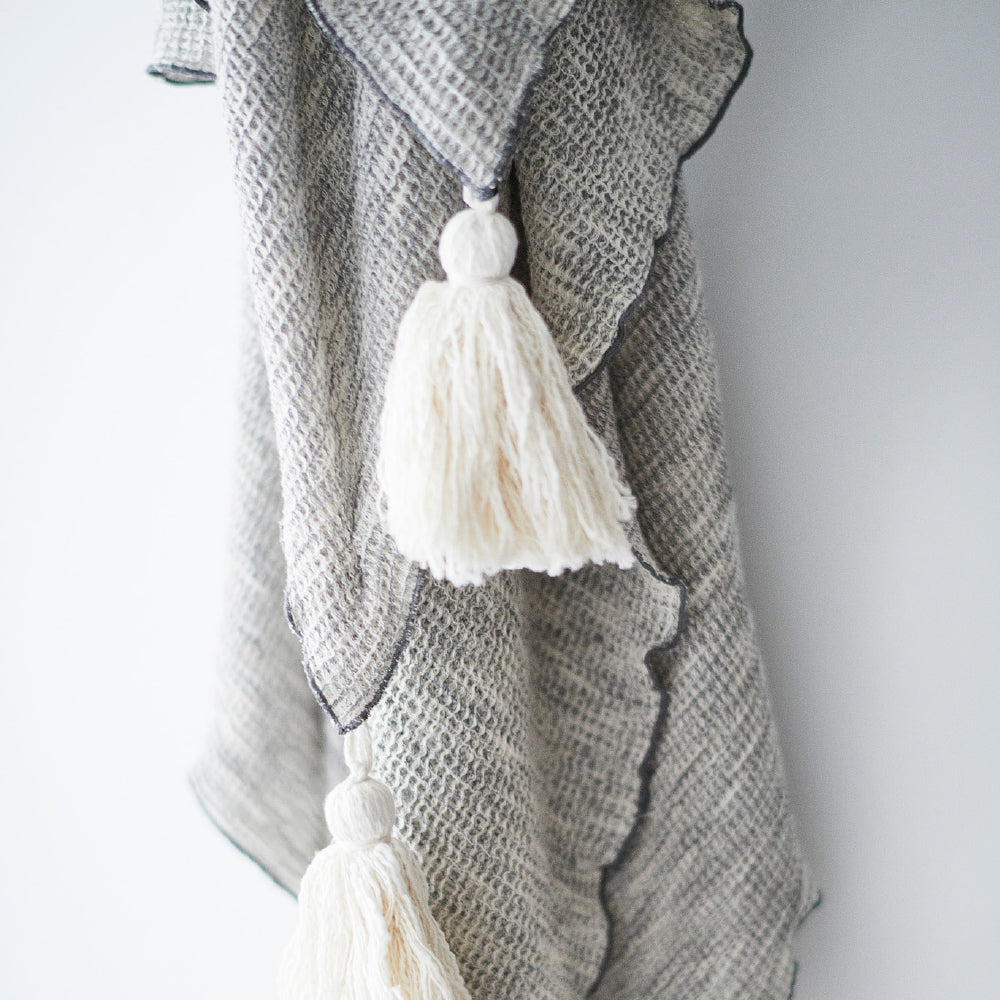 silver grey textured linen throw with cream tassels and lettuce trim edges