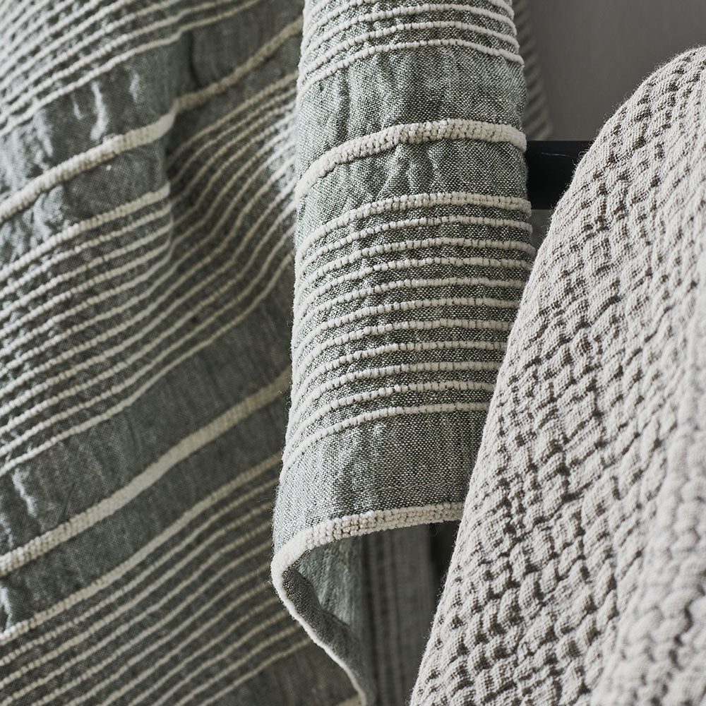 pistachio linen throw with a white stripe feature and tassels on the corners