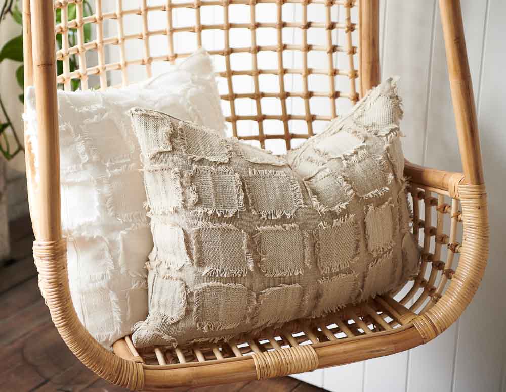 Bedu Cushion in natural and white sitting on a hanging chair