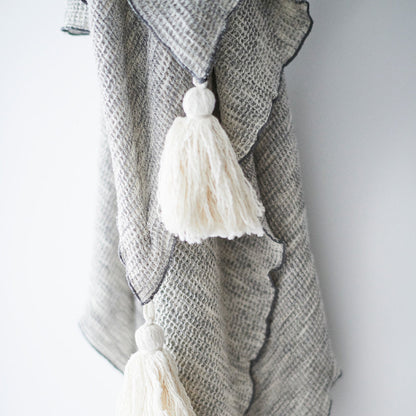silver grey textured linen throw with cream tassels and lettuce trim edges