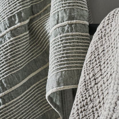 pistachio linen throw with a white stripe feature and tassels on the corners